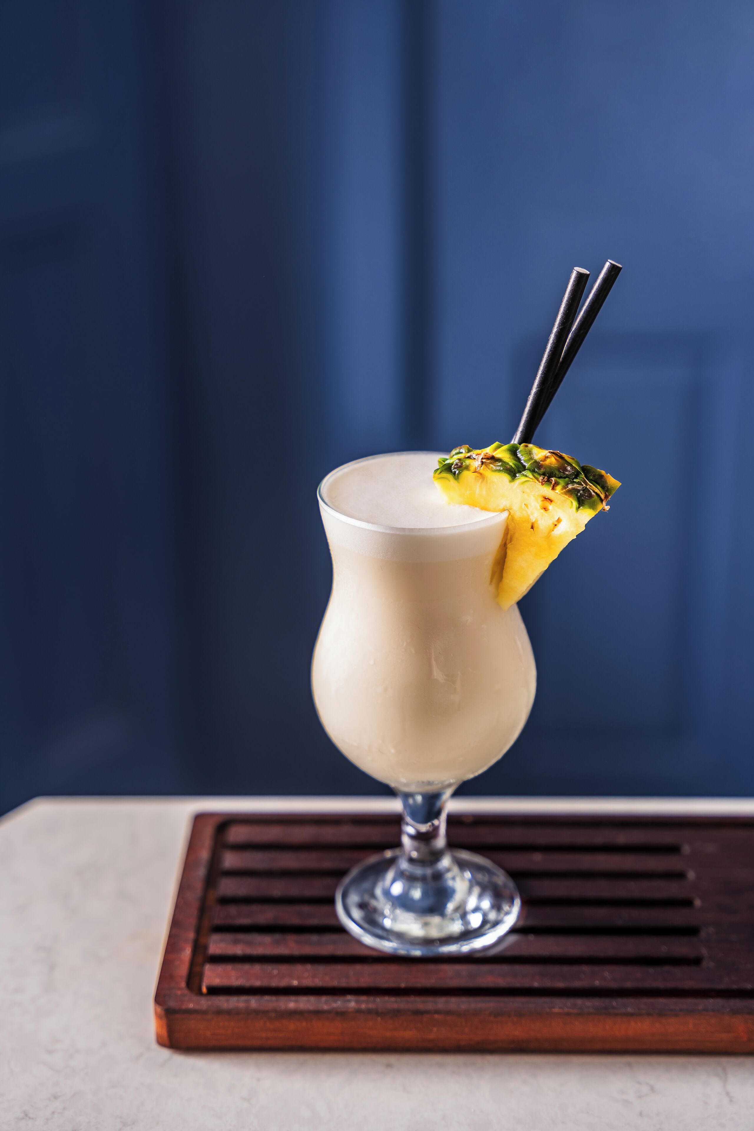 Un cocktail in un bicchiere, guarnito con ananas e una cannuccia.