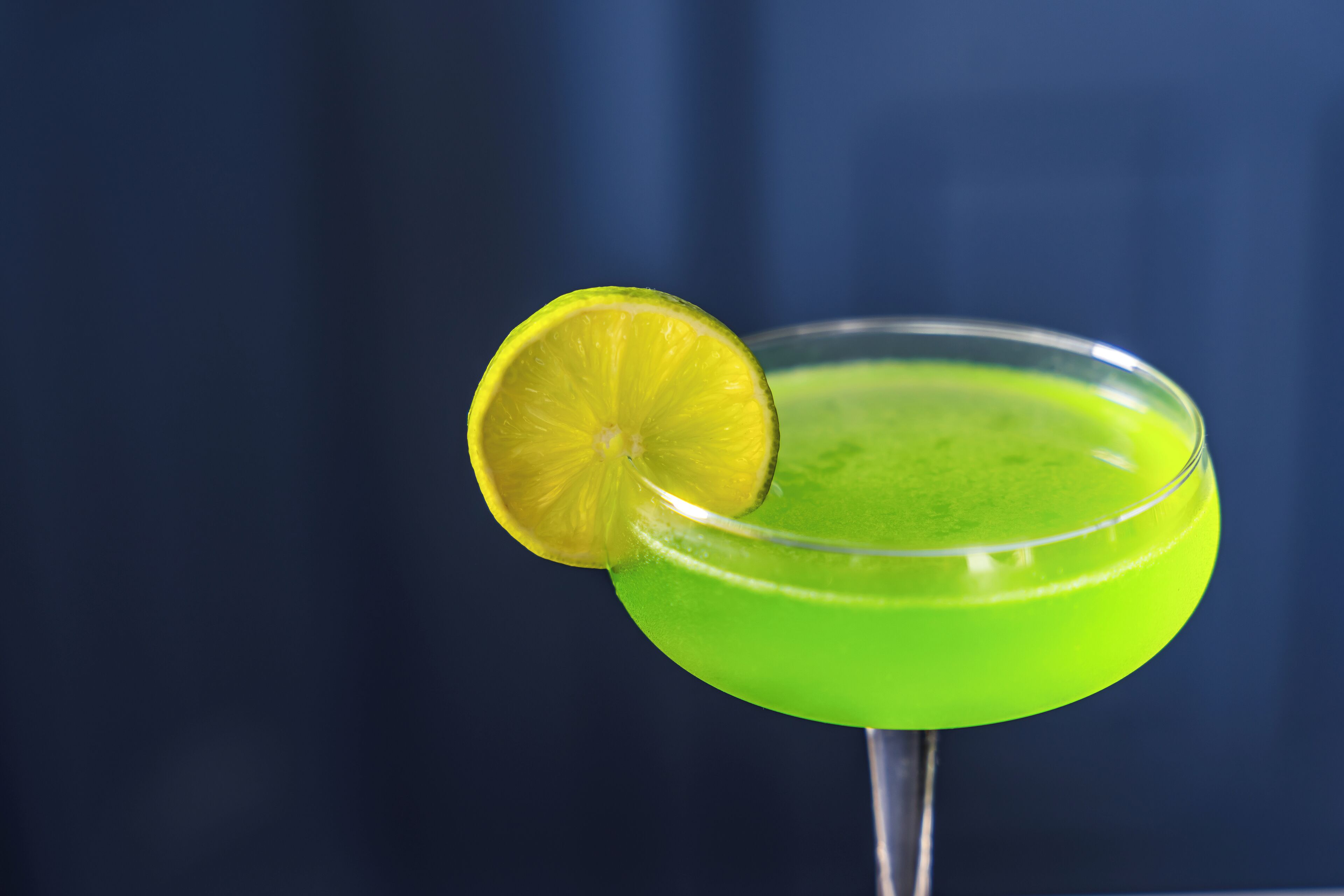 A cocktail in a glass with a lime garnish.