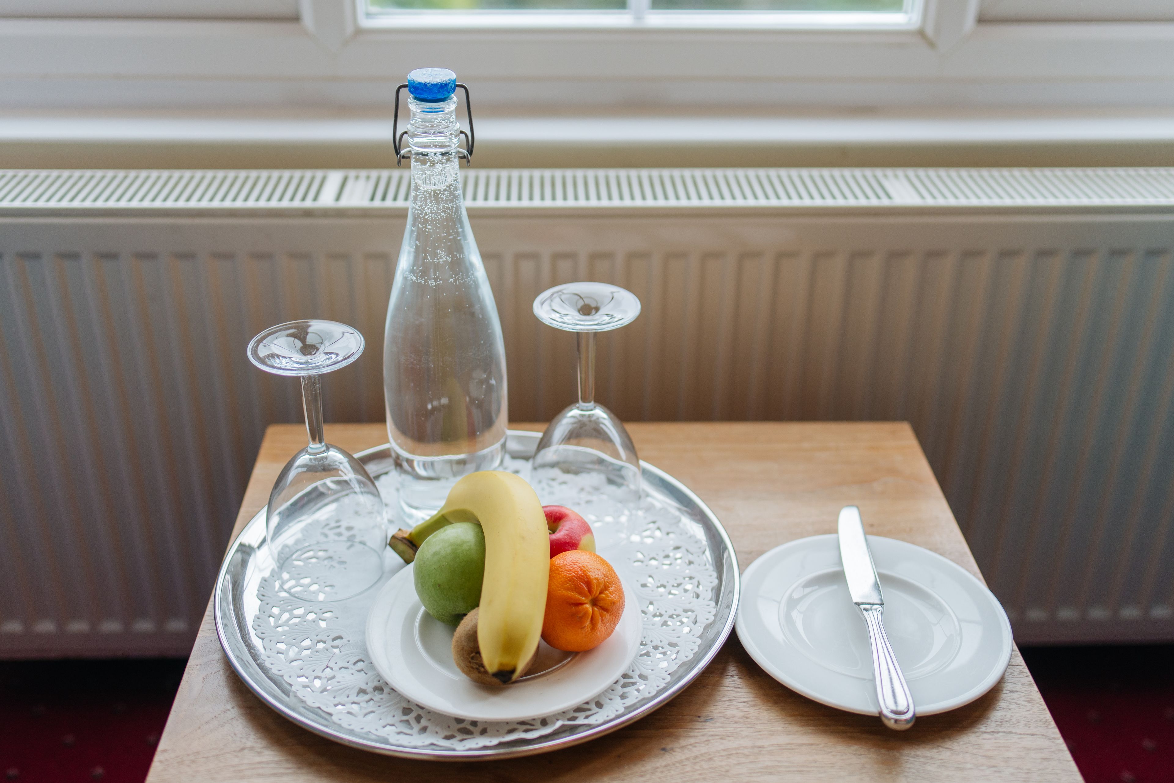 A table with a fruit plate, a bottle, a wine glass, and a knife.