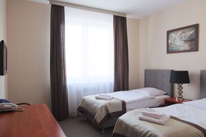 A hotel room with two beds, a desk, a telephone, a lamp, and a painting on the wall. - Centrum Konferencyjne Mrówka (Warsaw)