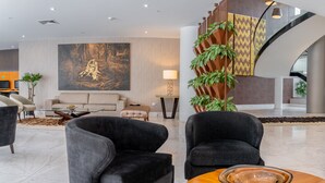 Un vestíbulo moderno con un sofá, sillones, una mesa de centro y una escalera.