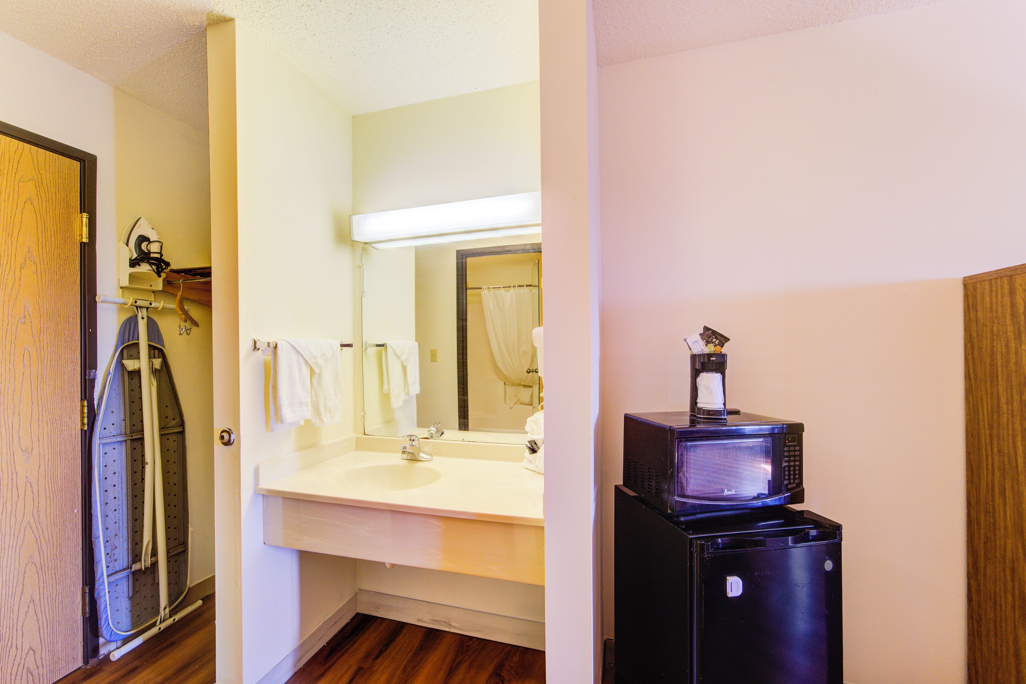 A bathroom with a sink, mirror, and a black refrigerator.