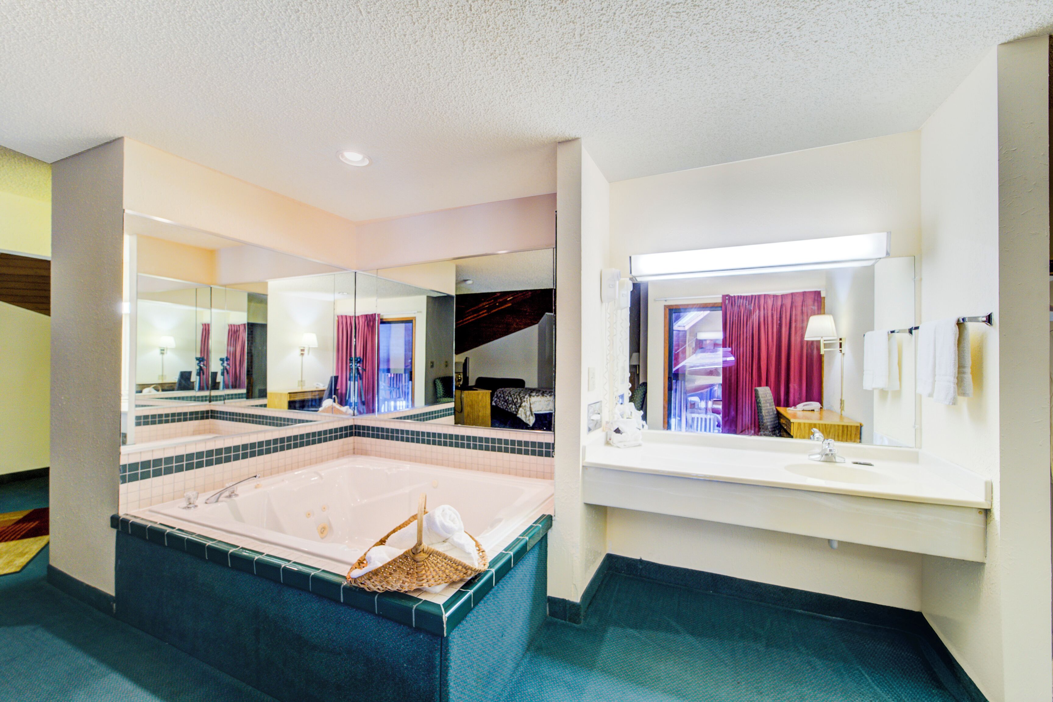 A modern bathroom with a large bathtub, a separate sink area, and a mirror reflecting the room.