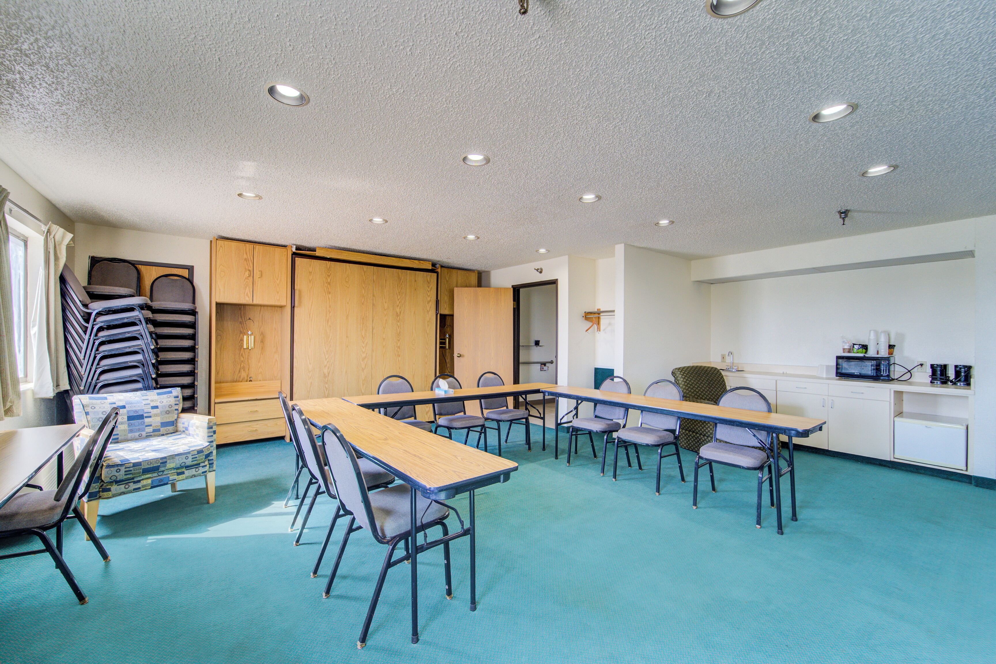 A conference room with a long table, chairs, and a kitchenette.