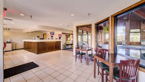A spacious lobby with a reception desk, a dining area with wooden tables and chairs, and large windows offering a view of the outdoors. - Capital O Amerihost Inn and Suites Mexico Hwy 54 MO (Mexico)