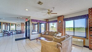 A spacious living area with a large sofa, a dining table, and chairs. There is a large window with a view of the outdoors. - Capital O Amerihost Inn and Suites Mexico Hwy 54 MO (Mexico)
