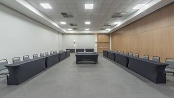 Un salón de conferencias con una larga mesa, sillas y un panel de pared de madera.
