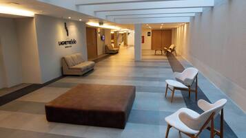 A hotel lobby with a reception desk, seating area, and a staircase leading to upper floors.