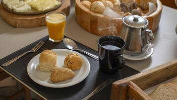 A breakfast setting with a plate of pastries, a coffee pot, and a glass of orange juice on a table.