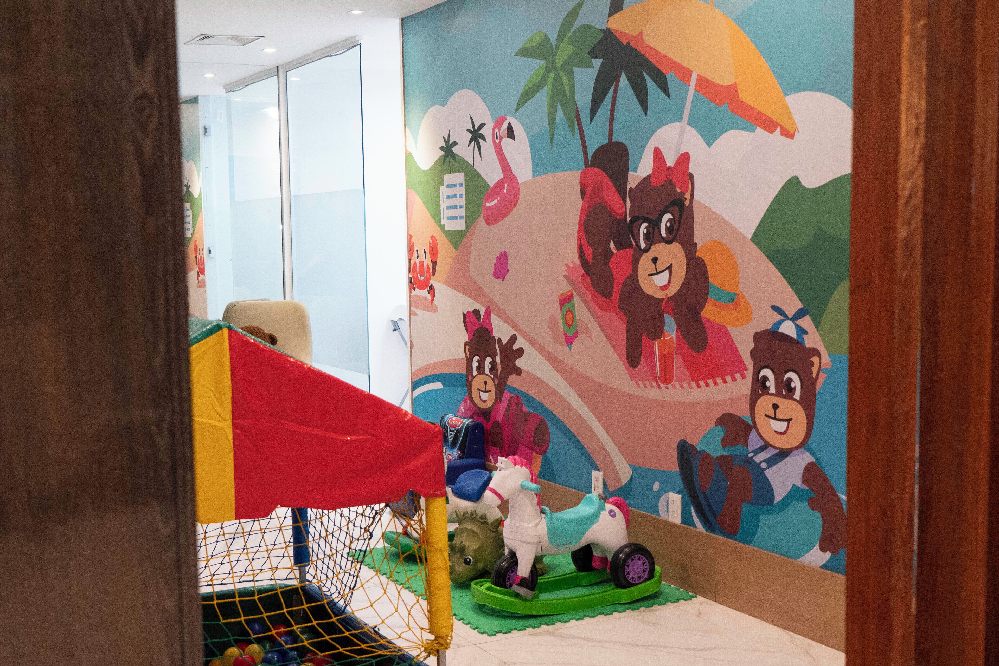 Un espace de jeux pour enfants agrémenté d’une fresque colorée, d’un petit toboggan intérieur et d’une structure de jeux en forme de filet.