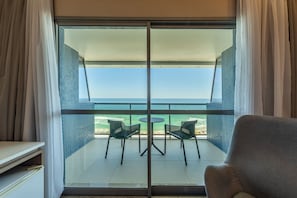 Enjoy ocean views from the balcony with a sliding glass door, featuring a table and chairs.