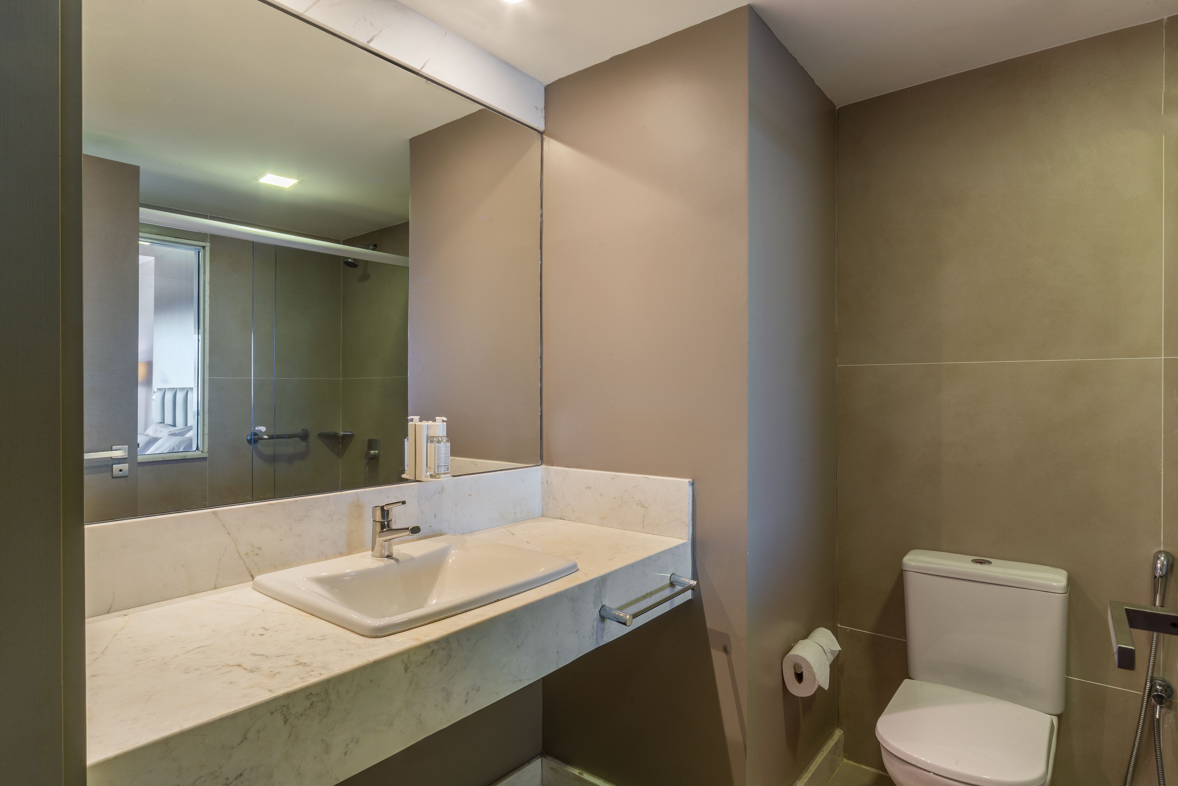 A modern bathroom with a marble sink, a toilet, and a mirror.