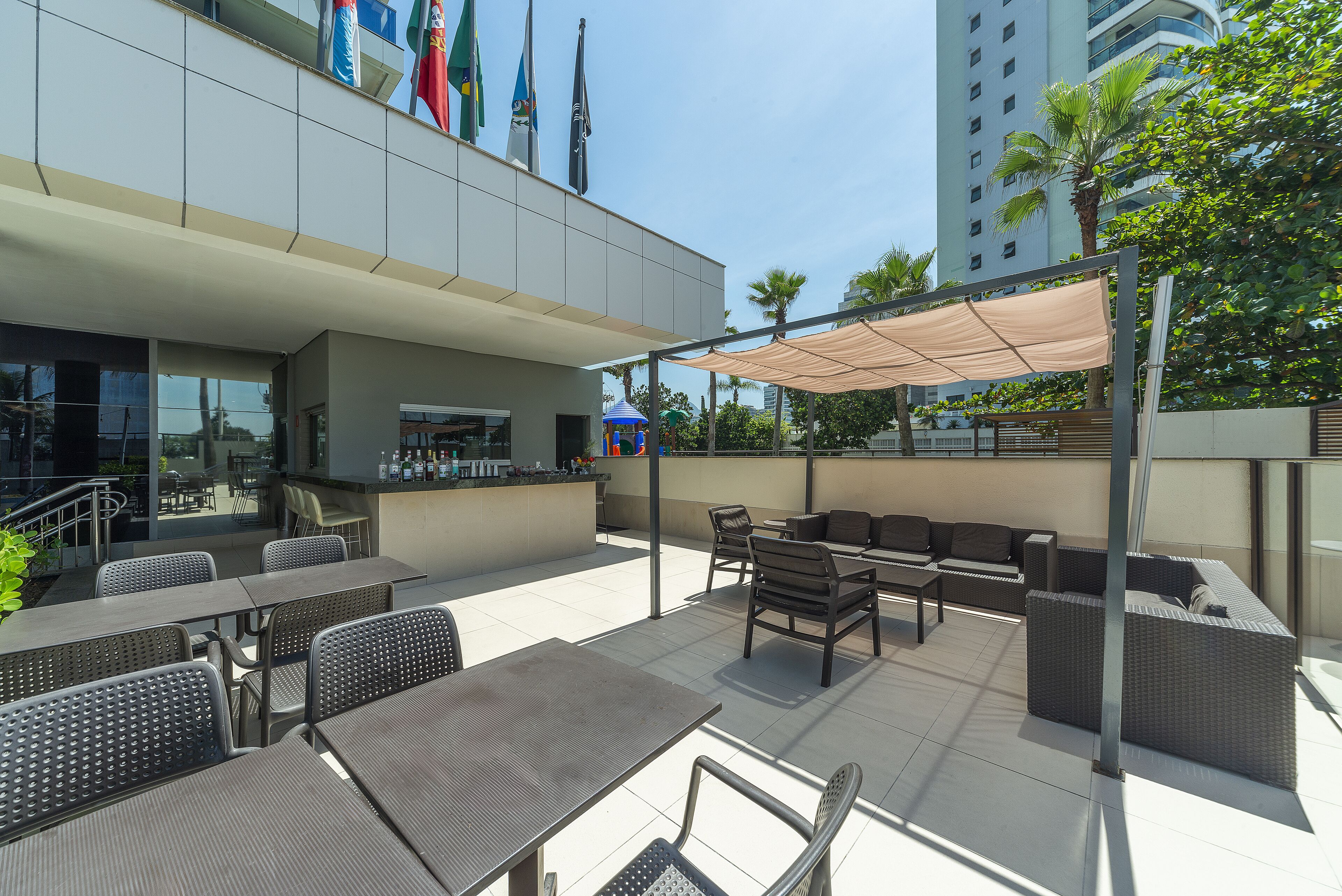 An outdoor patio area with tables and chairs, a bar, and a covered seating area.