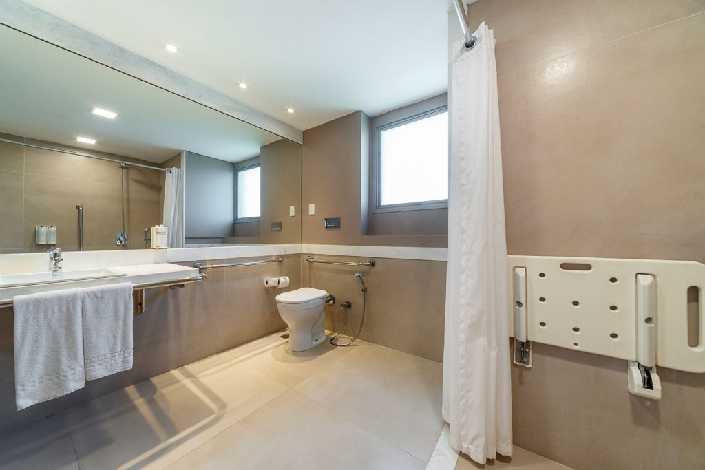 Un baño moderno con un espejo grande, inodoro y zona de ducha.