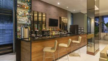 A modern bar area with a wooden counter, bar stools, and a variety of liquor bottles.
