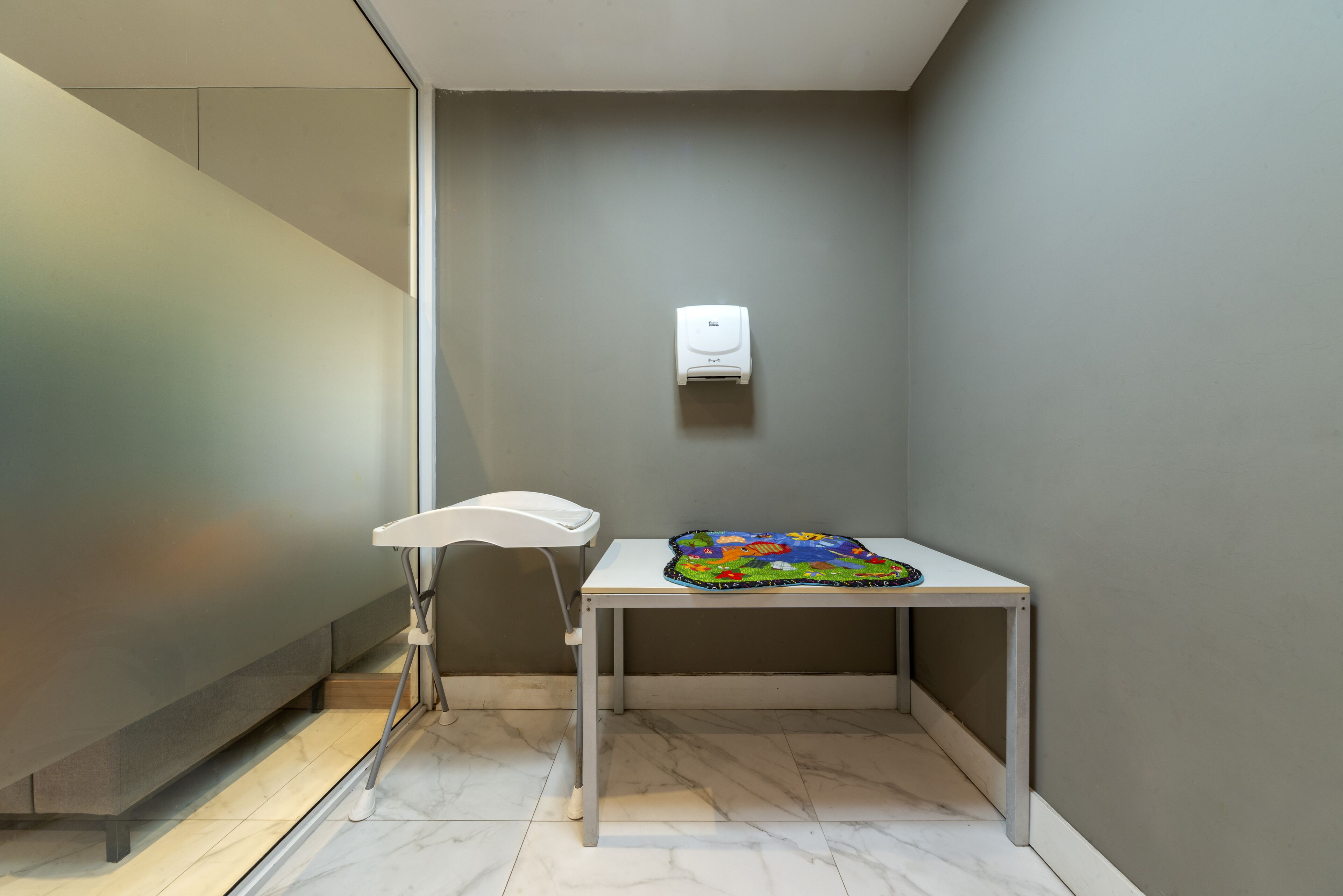 A small, modern room with a white table, a colorful rug, and a white chair.