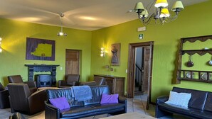 A room with a fireplace, leather sofas, a dining table, and a chandelier. - Holiday Home in Somme-Leuze with Garden BBQ (Noiseux)