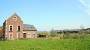 A brick building with a triangular roof, multiple windows, and a fenced yard. - Holiday Home in Somme-Leuze with Garden BBQ (Noiseux)