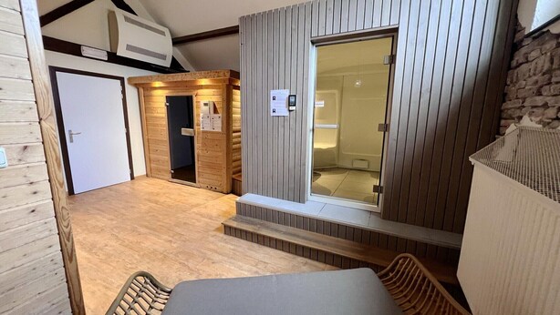 A room with a wooden floor, a bed, a window with blinds, a door, and a wall-mounted air conditioner. - Holiday Home in Somme-Leuze with Garden BBQ (Noiseux)