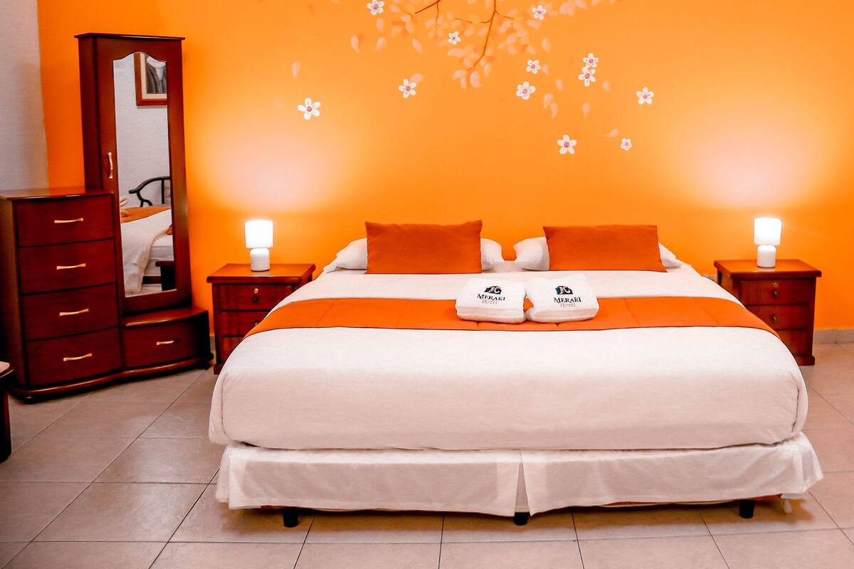 A hotel room with a large bed, two nightstands, a dresser, and a mirror.