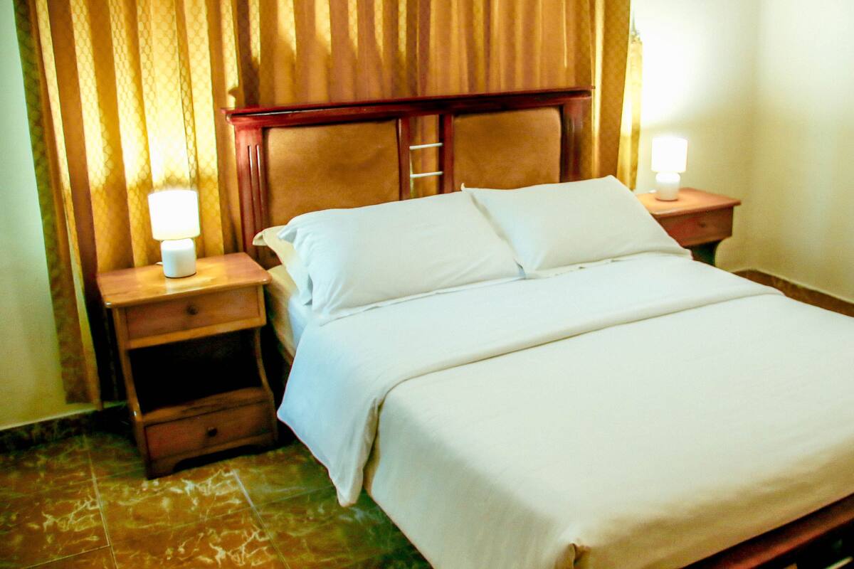 A hotel room with a bed, two bedside tables, and a nightstand.