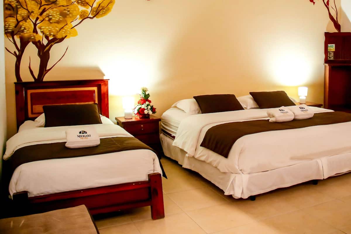 A hotel room with two beds, a nightstand, a lamp, and a decorative plant.