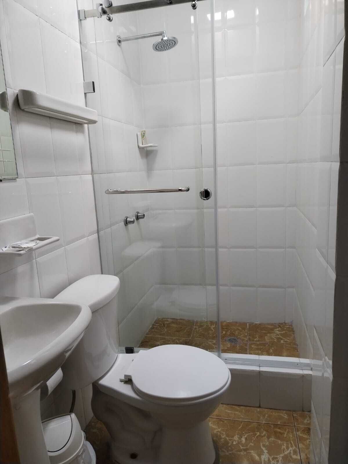 A small, enclosed shower stall with a glass door, a toilet, and a sink.