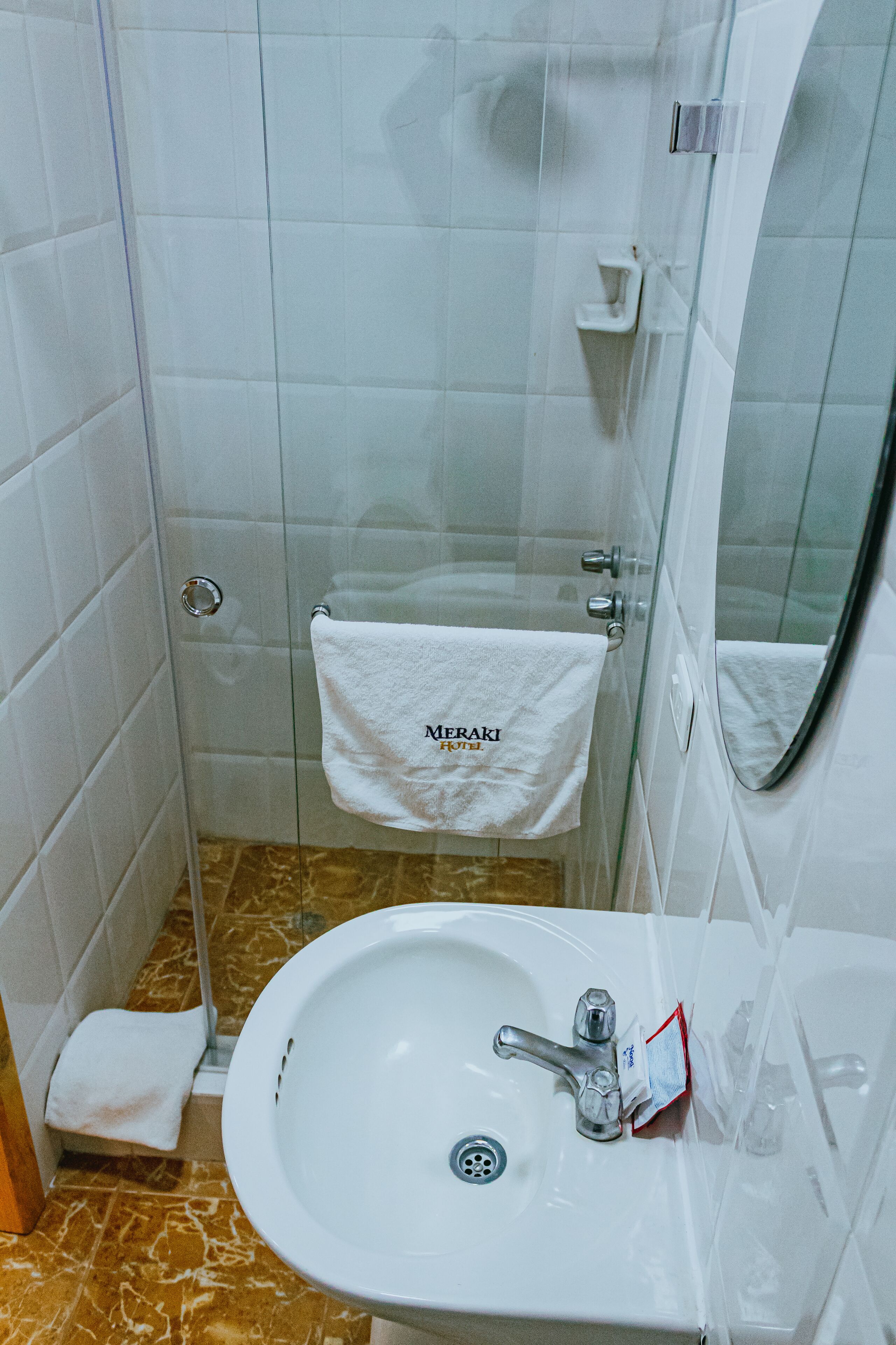 A bathroom with a white sink, a glass shower enclosure, and a towel hanging on the wall.