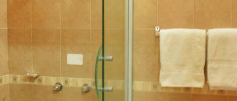 A bathroom with a glass shower enclosure, a sink, and a towel rack.