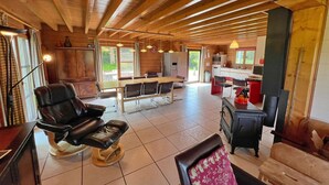 A spacious room with a wooden ceiling, a dining table with chairs, a fireplace, and a leather chair. - Chalet in Hampteau with Valley Views (Hampteau)