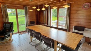 A wooden-paneled room with a large table and chairs, large windows, and a clock on the wall. - Chalet in Hampteau with Valley Views (Hampteau)