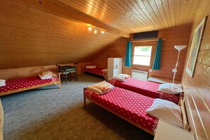 Une chambre mansardée agréable, dotée de deux lits simples, d’un petit bureau et d’une chaise.