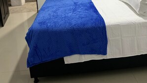 A bedroom with a bed, white bedding, a blue blanket, and an air conditioning unit on the wall. - Casa Torices Real 12  (Cartagena)