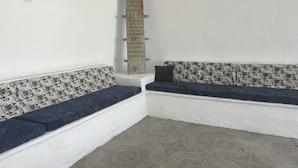 A corner of a room with a white wall, a wooden post with text, and a bench with patterned cushions. - Casa Torices Real 12  (Cartagena)