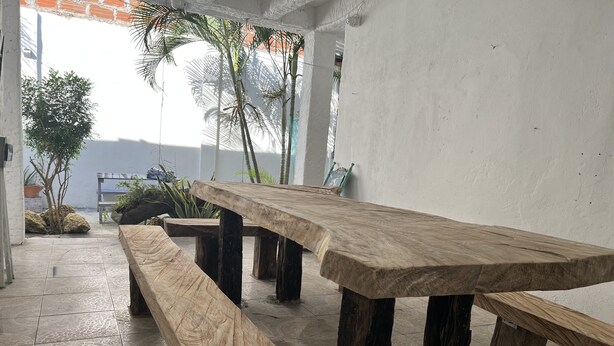 A long wooden bench and table set in a room with a tiled floor and white walls. - Casa Torices Real 12  (Cartagena)