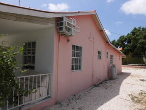 A pink building with a covered porch and a window with metal bars. - Curacao Vacation Homes (Willemstad)