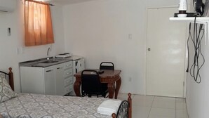 Une chambre à coucher comprenant un lit, un bureau, une chaise, une armoire et un téléviseur fixé au mur.