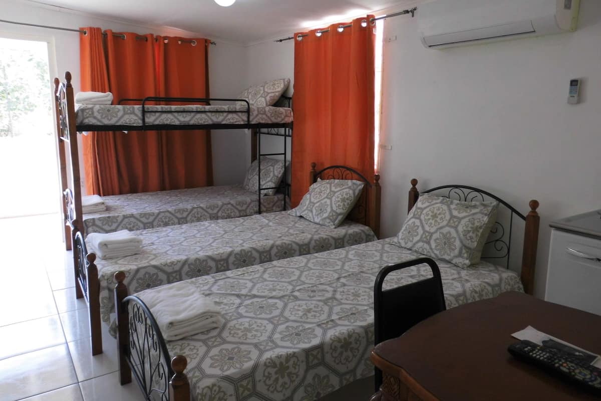 A dormitory room with bunk beds, a desk, and a chair.