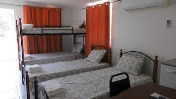 A dormitory room with bunk beds, a desk, and a chair.