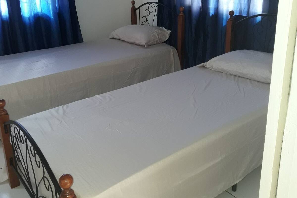Two single beds with wooden headboards, white linens, and blue curtains.