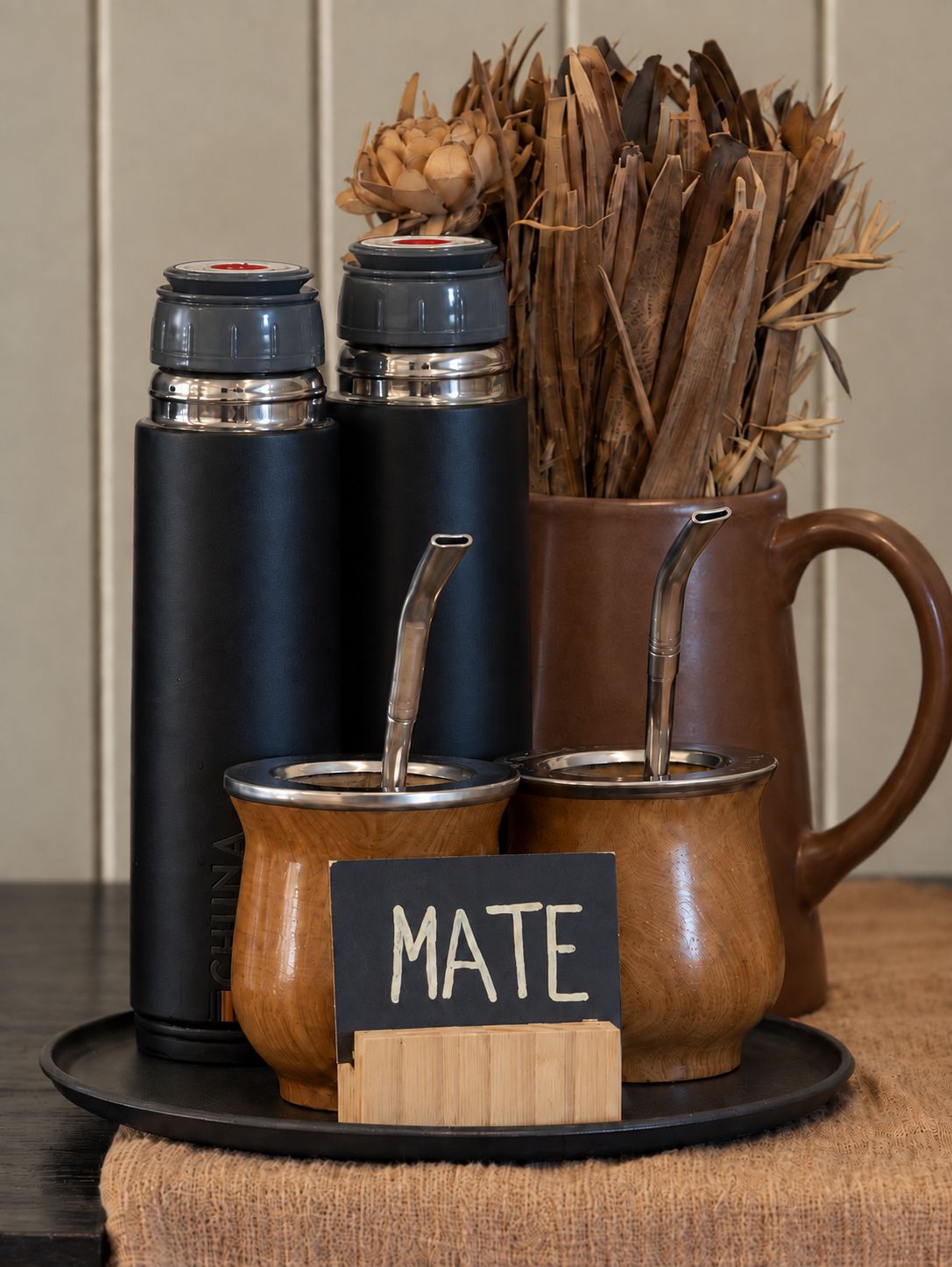 Un conjunto de termos y una taza sobre una bandeja con un cartel que dice 'MATE'.