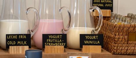 Se exhiben bebidas como leche fría, yogur de fresa y yogur de vainilla, junto con un tarro de aceite y un frasco de mermelada.