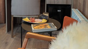 A compact kitchenette with a built-in fridge, a coffee maker, and a small dining area with a chair and table.