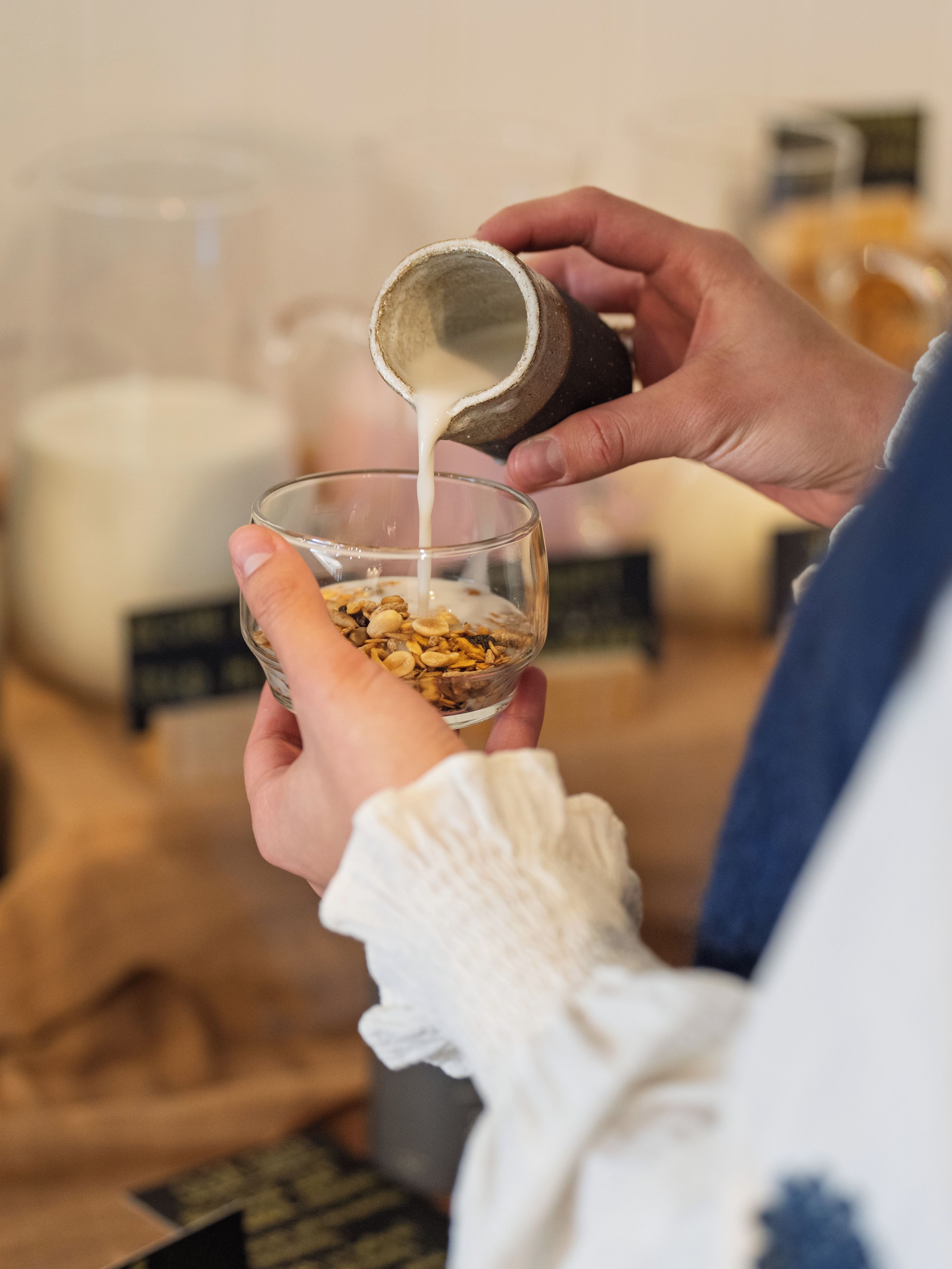 A person pouring milk into a bowl of cereal.