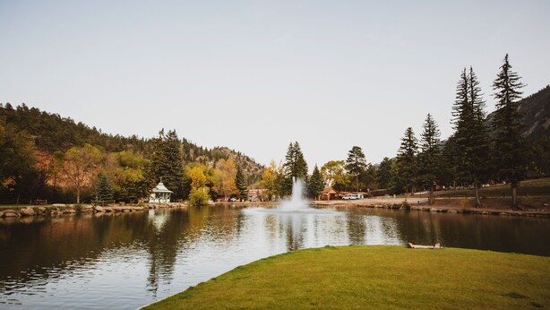 A tranquil lake with a gazebo, trees, and a fountain. - Little Beaver Inn (Green Mountain Falls)