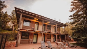 A modern two-story house with a covered patio, outdoor seating, and a stone wall. - Little Beaver Inn (Green Mountain Falls)