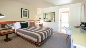 A hotel room with a large bed, bedside tables, a desk, a chair, a mirror, and a window with blinds. - Little Beaver Inn (Green Mountain Falls)