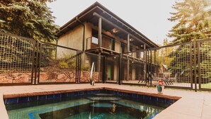 A swimming pool with a stone border, a metal fence, and a building with a balcony. - Little Beaver Inn (Green Mountain Falls)