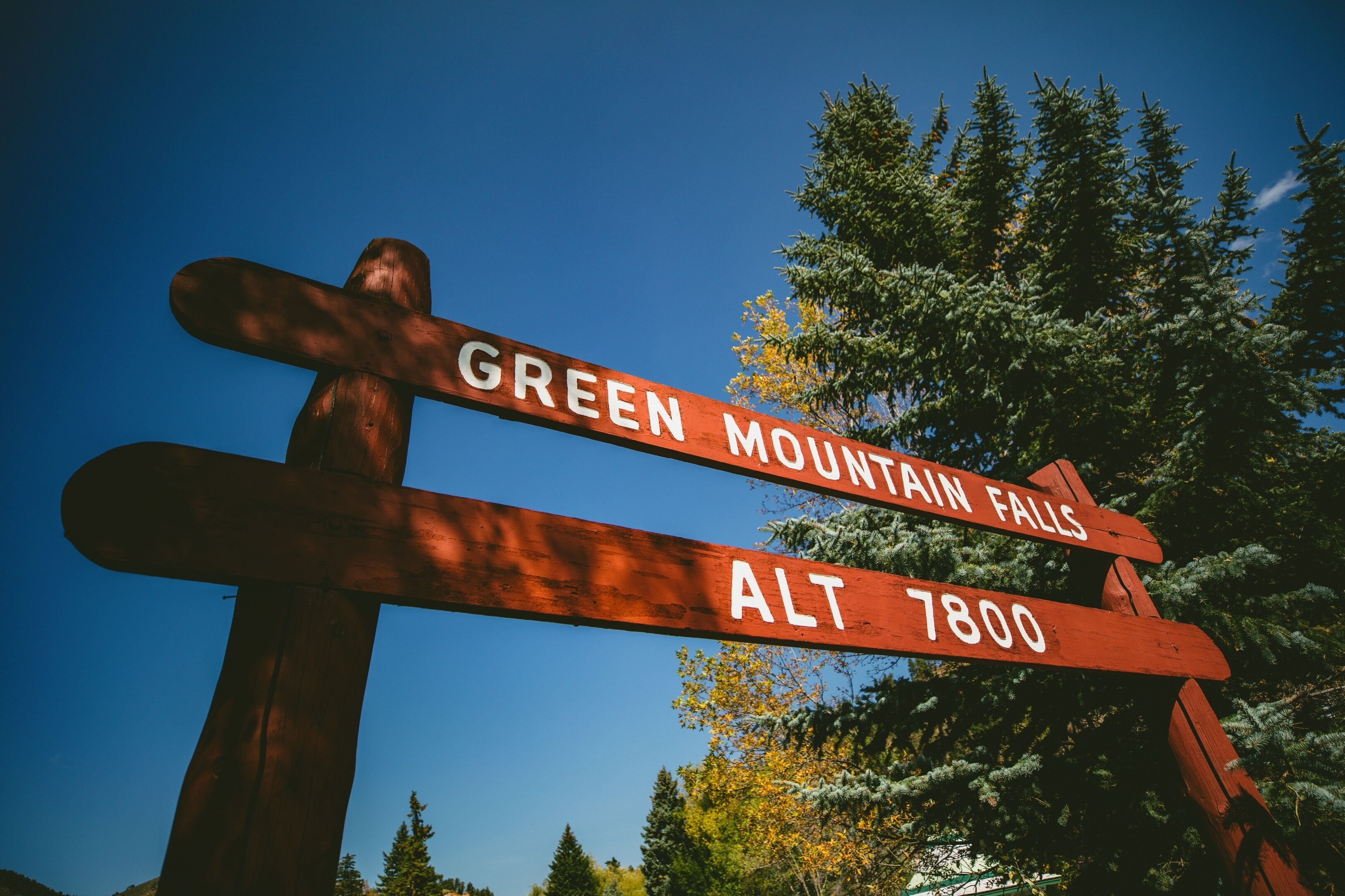 Um painel de madeira com indicações para Green Mountain Falls e Alt 7800.