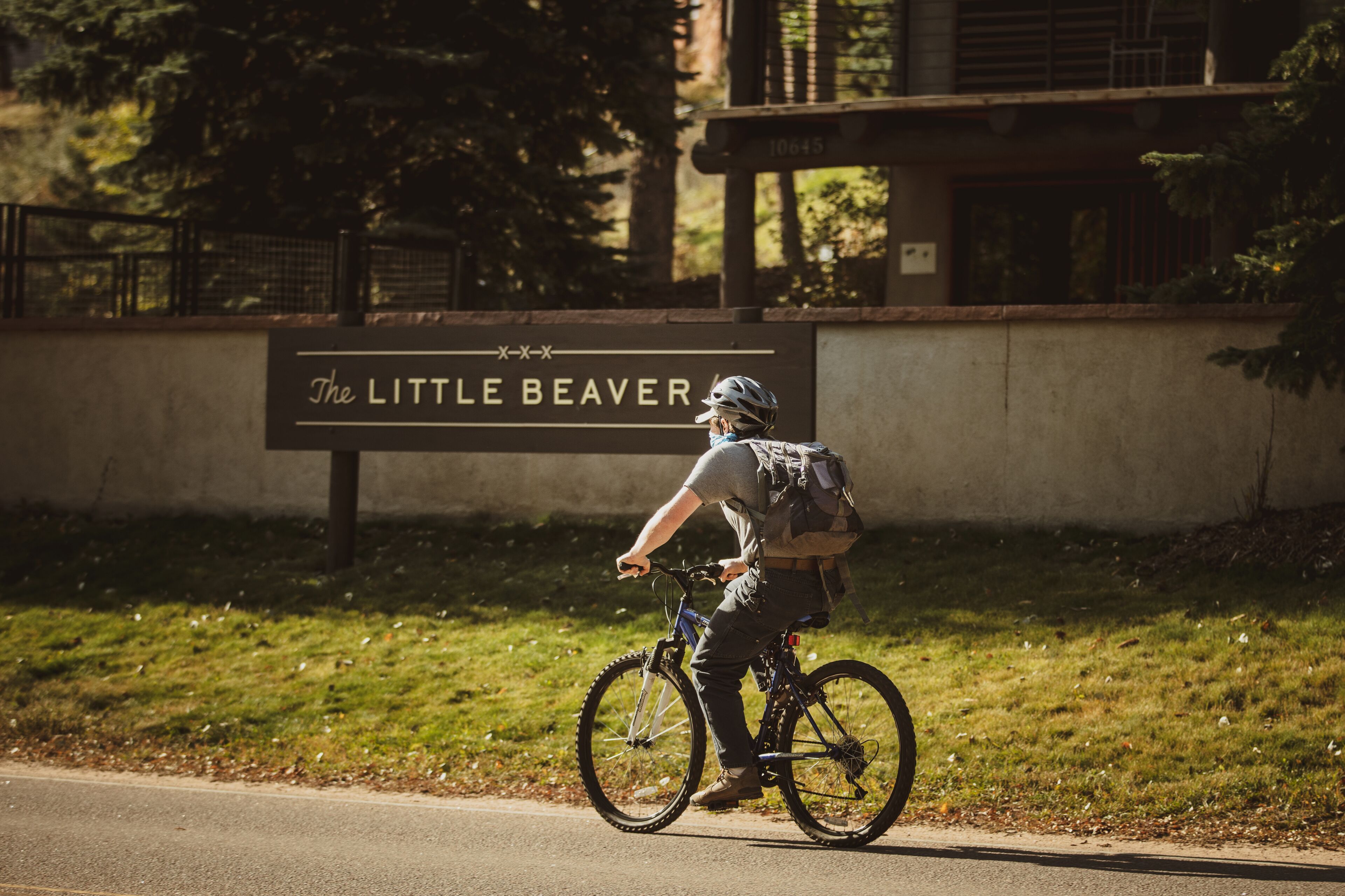 Una persona montando en bicicleta frente a un cartel que dice 'The Little Beaver'.